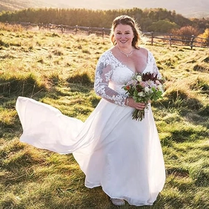 Detailed view of the floral lace appliqué and sheer long sleeves of the bridal gown