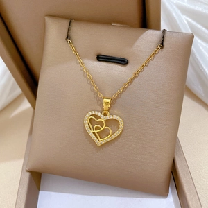 Close-up of golden double heart pendant necklace with shimmering crystals in a luxury gift box