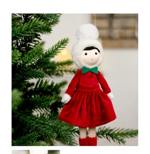Close-up of handmade velvet Christmas girl doll hanging on a festive evergreen branch