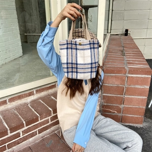 Detail of wool bento handbag featuring blue and brown plaid pattern with magnetic clasp