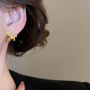 Close-up of golden unicorn stud earring with rhinestones on a model ear lobe
