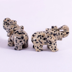 Macro shot of two carved elephant statues made of black and white spotted stone texture