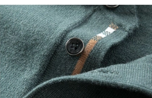 Nahaufnahme von dunkelgrünem Strickstoff mit gestreiftem Kragen und schwarzen Knöpfen