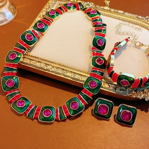 Vintage jewelry set with green enamel squares and red gemstones in ornate gold frames