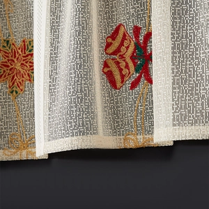 Detail of Christmas lace curtain showing embroidered bells, red bows and poinsettia patterns