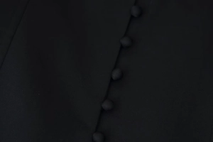 Close-up of elegant cloth-covered buttons on minimalist black V-neck long sleeve jacket
