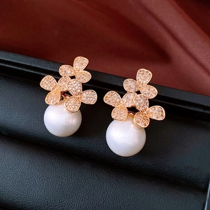 Makroaufnahme von roségoldenen Blumenohrringen mit Zirkonia-Pavé und großen weißen Perlen