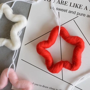 Macro view of handmade wool felt star ornaments in red, white and pink for Christmas