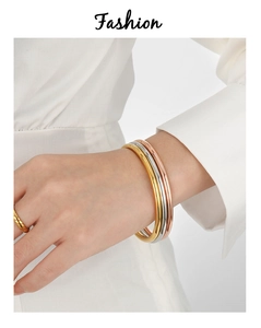 Close-up of three stacked minimalist 4mm solid metal bangles in gold, silver and rose gold