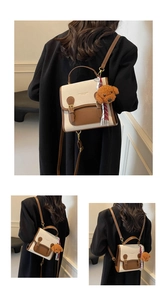 Detailed view of canvas and leather crossbody bag with teddy bear charm and striped scarf
