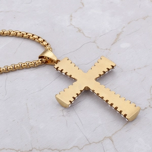 Close-up of a gold hip hop cross pendant with small zircons on white marble