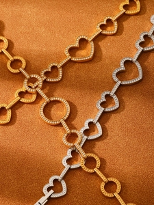 Macro shot of gold and silver heart-shaped pavé bracelets on orange velvet background