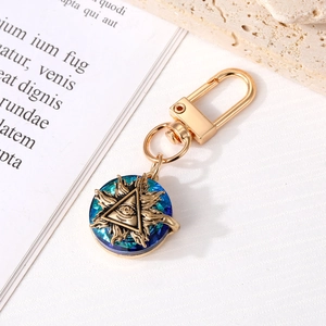 Detail of golden evil eye keychain with blue crystal on textured white surface