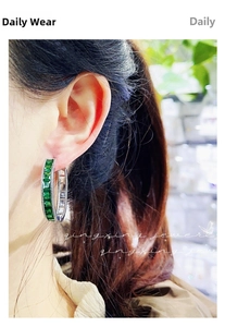 Macro shot of emerald green rectangular diamonds set in a silver-tone C-hoop earring