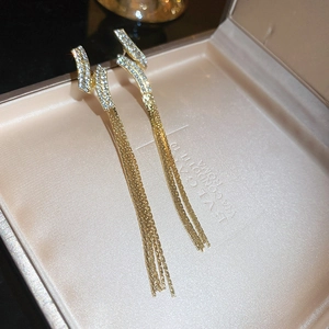Detailed close-up of golden tassel earrings with Z-shaped geometric pavé crystals