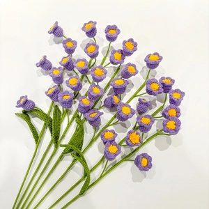 Detail of handmade crochet purple lily of the valley bouquet with green yarn leaves
