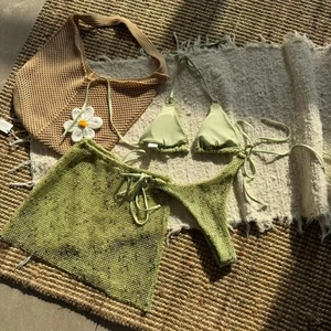 Detailed view of light green 3-piece bikini set with mesh sarong on a textured beach mat