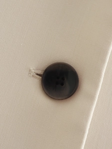 Macro shot of dark brown four-hole buttons on beige knitted fabric of a Y2K tank top