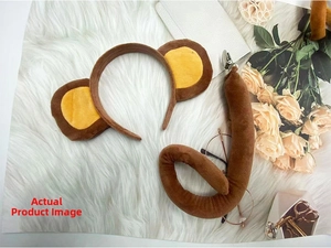 Close-up of brown monkey ears headband and plush tail set on a soft white background