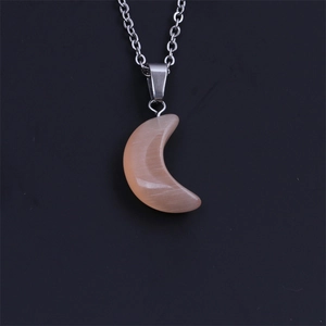 Gros plan sur chaîne argentée avec pendentif lune en pierre de lune pêche sur fond noir