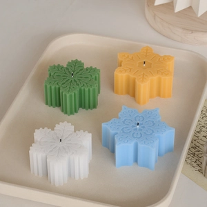 Detail van sneeuwvlokvormige geurkaarsen in de kleuren groen, geel, wit en blauw