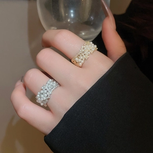 Close-up of gold and silver pearl rings with diamonds worn on fingers