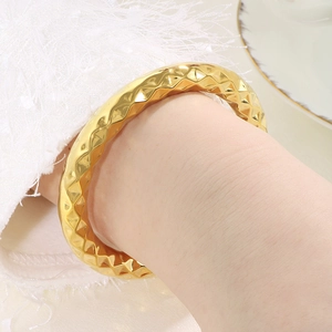Detailed close-up of a gold stainless steel bangle with a stylish quilted diamond pattern