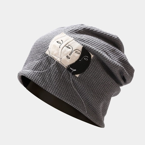Detail shot of grey waffle knit slouchy beanie featuring minimalist face patch