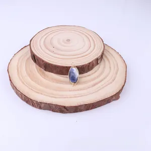 Close-up of handmade gold wire-wrapped blue natural stone pendant on wooden slices