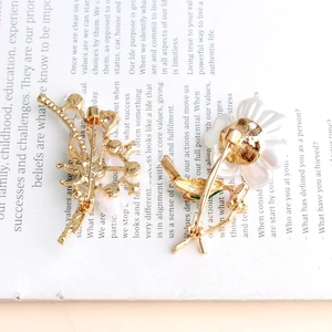 Detail view of gold flower brooches with white enamel on vintage book pages background