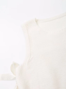 Detail shot of cream white knit vest showing side ribbon bow and soft fabric texture