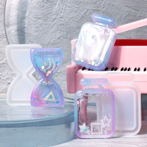 DIY hourglass and perfume bottle silicone molds with glitter resin charms on blue stand