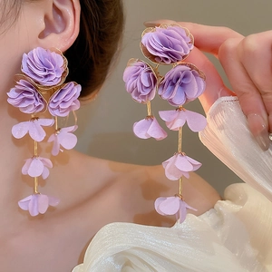 Detailed close-up of purple chiffon flower tassel earrings worn by a model