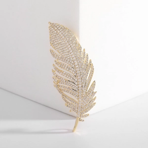 Exquisite golden feather brooch with clear zircon inlay on white cubic background