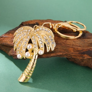 Détail du porte-clés palmier doré orné de strass brillants et de perles blanches élégantes