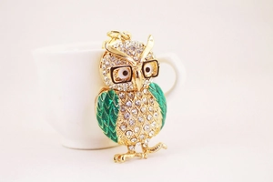 Détail du porte-clés hibou avec base en métal doré, strass et ailes en émail vert