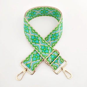 Close-up of jacquard woven strap with green geometric patterns and gold metal clips