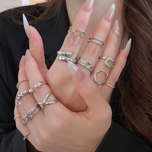 Close-up of stacked silver starfish and geometric open rings worn on model fingers