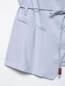 Macro detail of light blue trousers with decorative tie belt and dark brown wooden beads