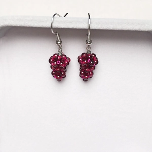 Macro shot of handmade dark red garnet beads woven into grape-shaped drop earrings