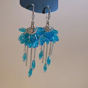 Macro detail of fan-shaped crystal earrings with blue tassels and sparkling zircons