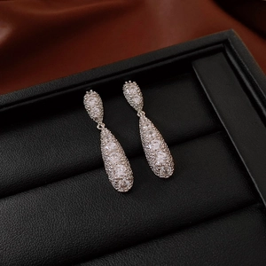 Macro shot of silver drop earrings with pavé-set zircons on a black leather tray