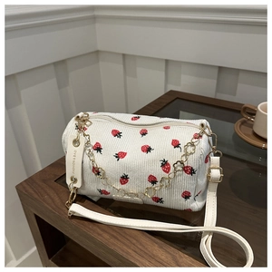 White corduroy cylinder bag with red strawberry print and golden chain strap