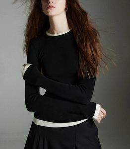 Detail of contrast stitching on neck and cuffs of slim-fit black wool knit top