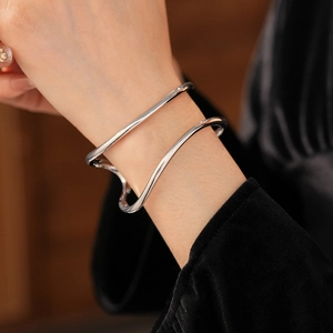 Gros plan d'un bracelet ouvert argenté poli à double vague sur une manche noire
