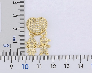 Dettaglio del ciondolo a cuore dorato con figure di bambini e righello graduato