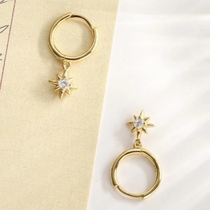 Macro shot of S925 sterling silver stamp and white zircon on golden star hoop earrings