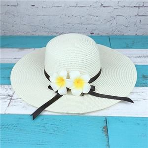 Detail of wide brim straw sun hat featuring elegant frangipani flowers and black ribbon