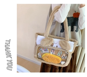 Detail of plush dog-shaped tote bag featuring a transparent PVC pocket and anime charms