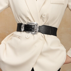 Detail of western retro wide black belt with faux crocodile texture and shiny rhinestone buckle